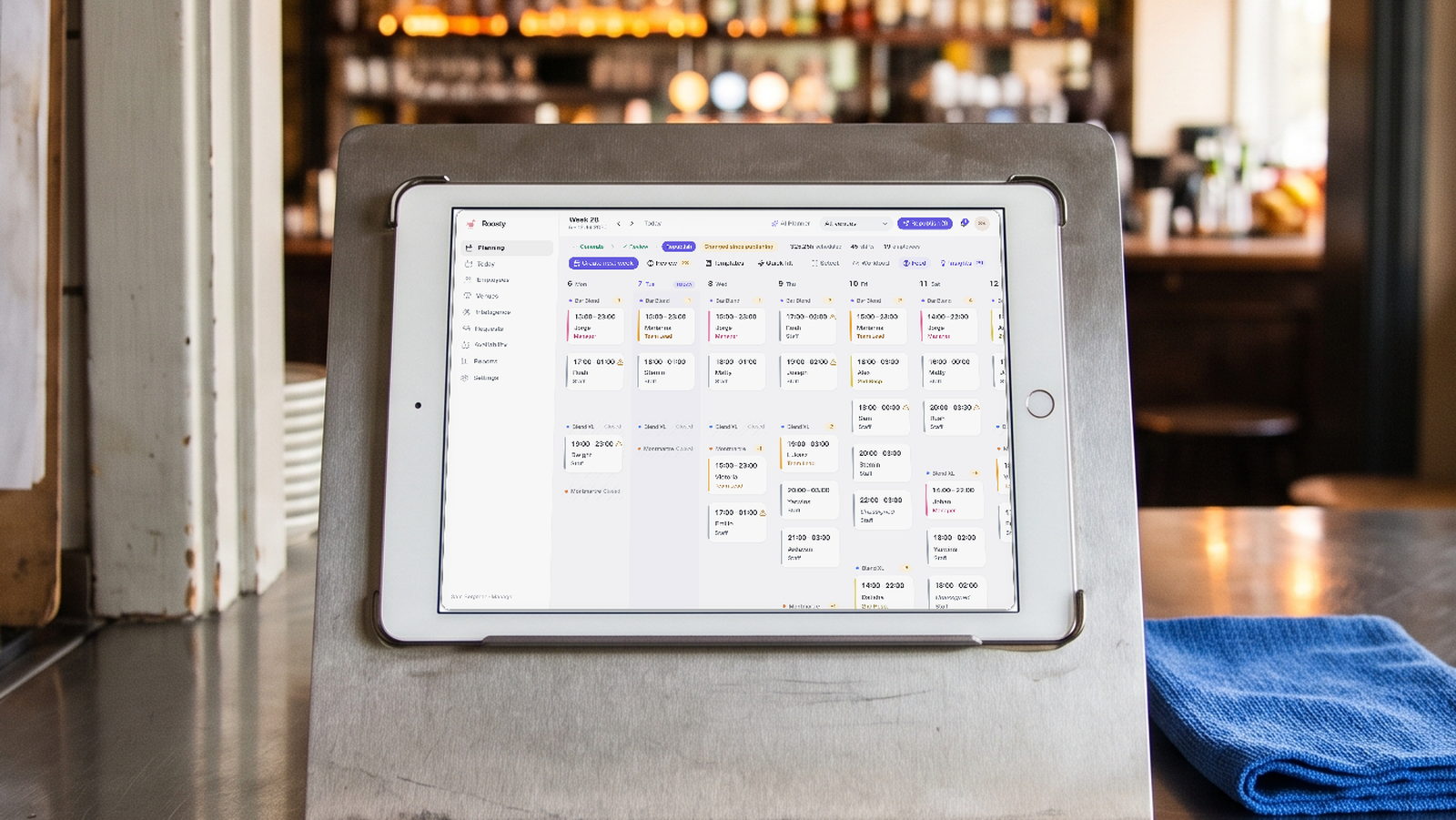 Roosty: the week planning board with shifts per venue on a tablet on the bar, next to the handwritten roster