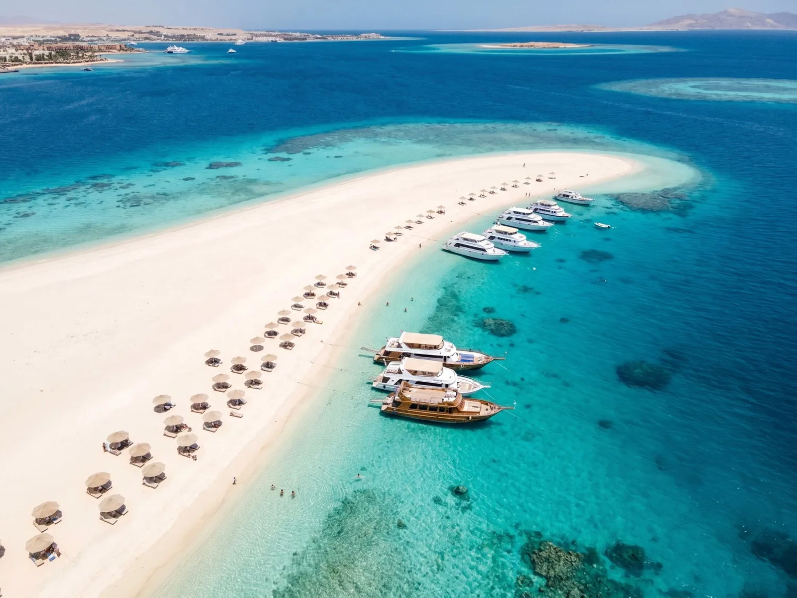 Orange Bay bij Hurghada: een witte zandbank, turkoois ondiep water en een boot voor anker onder een strakblauwe lucht.